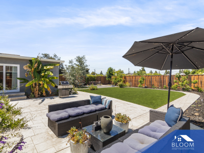 Modern backyard patio with outdoor seating and lush greenery.