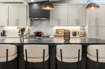 Modern kitchen with grey cabinets, marble countertops, and elegant lighting fixtures.