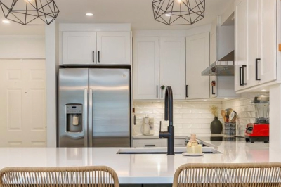 Modern kitchen with white cabinetry, stainless steel appliances, and a large kitchen island with bar seating.