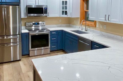 Modern kitchen remodel with blue and white cabinetry and stainless steel appliances.