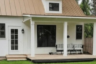 Modern accessory dwelling unit (ADU) with white siding and black trim in a landscaped backyard.