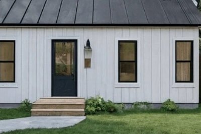 Cozy detached ADU with covered porch and large windows in a green backyard.