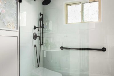 Luxury bathroom with walk-in shower, white tiles, and black fixtures.