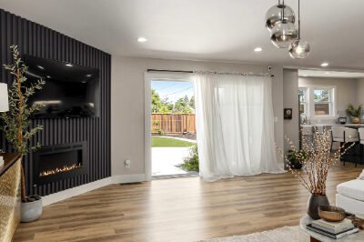 Open-concept living room with natural lighting, hardwood floors, and a modern fireplace.